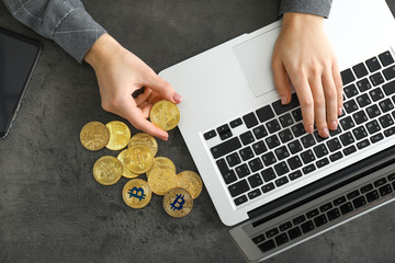 Wall Mural - Businesswoman with bitcoins and laptop at table