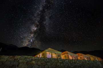 Wall Mural - milkyway galaxy shining above illuminated tents near pangong lake, ladakh