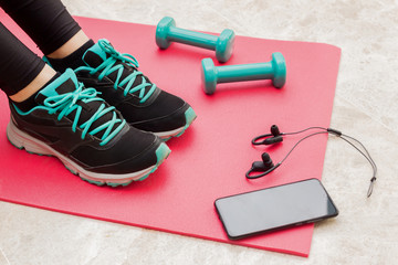 Wall Mural - Stock photo of a young woman resting after exercising at home in the living room