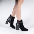black leather female high-heeled ankle boots on model legs shooting in studio on a white background