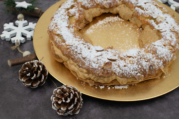 French dessert paris-brest whit sugar powder and almonds on the golden plate