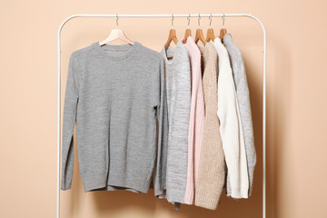 Wall Mural - Warm sweaters on a wardrobe hanger on a colored background. Autumn, winter clothes.