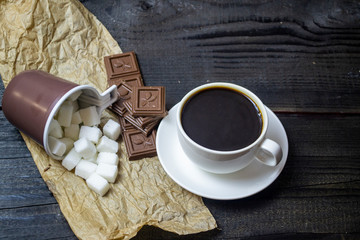 white cup with coffee, with chocolate and sugar on a black background