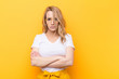 young pretty blonde woman feeling displeased and disappointed, looking serious, annoyed and angry with crossed arms against flat color wall