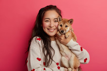 Pleased Brunette Woman Plays With Pedigree Dog, Embraces Shiba Inu, Enjoys Spare Time, Expresses Loyalty From Four Legged Friend, Carries Animal To Vet Clinic, Has Toothy Smile. Lovely Pet With Owner