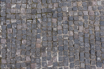 Granite dirty paving stones in the city. Road from paving stones for background and texture. The old road of granite paving stones.