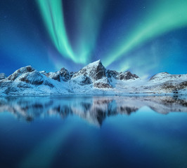Wall Mural - Mountains and northern lights in the sky. Reflections of the night sky and mountains on the water. Winter landscape in Norway