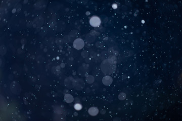 Abstract snow or rain bokeh texture overlay on blue background.