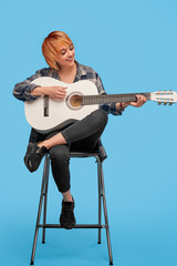 Cheerful woman playing guitar on chair