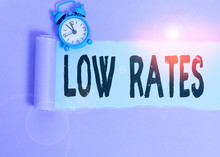 Text Sign Showing Low Rates. Business Photo Showcasing A Cost Of An Item Or Service Which Is Usualy At Its Smallest Price Alarm Clock And Torn Cardboard Placed Above Plain Pastel Table Backdrop