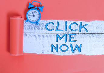 Poster - Handwriting text writing Click Me Now. Conceptual photo Internet helping desk Press the button Online Icon Nertwork Alarm clock and torn cardboard placed above a wooden classic table backdrop