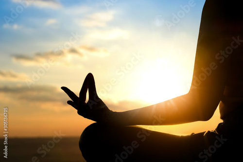 Fotografía Silhouette of a woman doing meditation on the beach of the sea during the morning hours