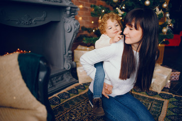 Poster - Beautiful mother in a white sweater. Family in a christmas decorations. Little boy in a room