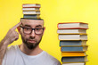 © _KUBE_ - Concept of education. A bald, bearded man with glasses points a finger at his head, which is filled with books. Nearby is a stack of books. Yellow background