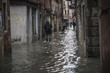 Venice, Veneto, Italy; 11/15/2019: Locals and tourists endure the worst flood in more than 50 years in Venice lagoon. People pass the flooded streets of the city.