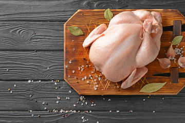 Raw chicken with spices on wooden background