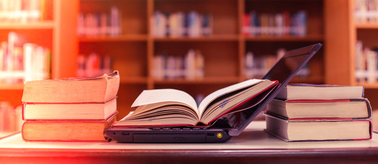 Poster - stack of books with laptop on table in library.