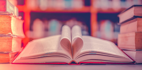 Poster - Stack of books in the library and blur bookshelf background