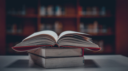 Poster - Stack of books in the library and blur bookshelf background