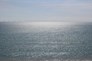 Wall Mural - Sparkling sea with wind turbines on the horizon