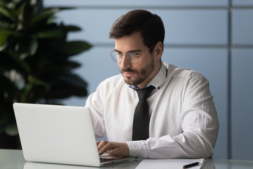 Wall Mural - Serious male employee busy using modern laptop in office