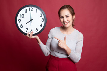 Wall Mural - Young Asian woman point to a clock.