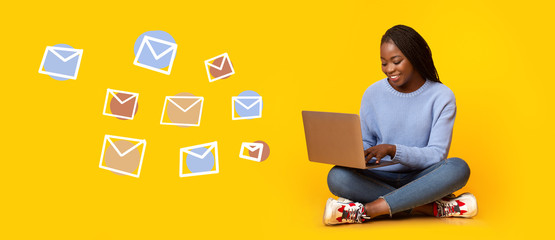 Woman typing text message on laptop, flying email envelopes