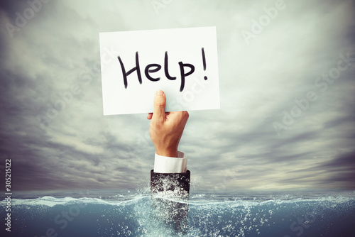 Fotografía Businessman drowning in the sea with a hand holding a sheet of paper with help w