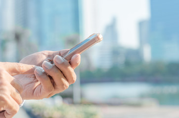 close up business man using hand typing smartphones and touch screen working search with app devices outdoor in city with sunrise and building background. 5G technology connecting the world.