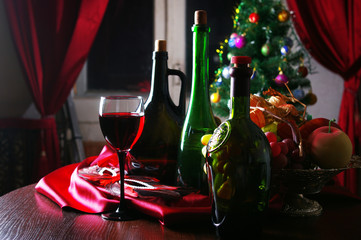 Canvas Print - Glass of red wine, three bottles and Christmas decorations in the interior