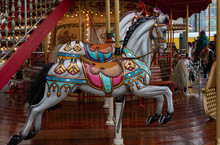 Carousel With Horses. Ornate Painted White Toy Horse Of Vintage Carousel In French Style. Retro Colorful Illuminated Merry-go-round With Golden Shiny Lights. Kids Playground At Christmas Funfair 
