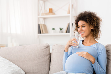 Water balance. Pregnant woman drinking water at home