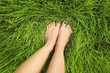 Pedicure with green nail Polish on the background of young grass in summer on the lawn.