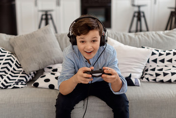 Handsome brunette boy in headphone playing video game and smile