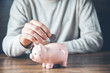 © ARAMYAN - man hand coins with piggy bank on desk