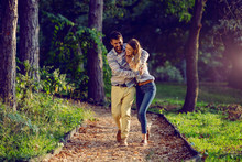 Happy Young Caucasian Couple Hugging And Walking On Trail In Woods. Weekend Activities.