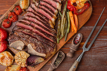 marbled beef steak on the bone cooked to a state of medium rare grill. next to the steak, grilled vegetables serving as a side dish. lovely gala dinner for two