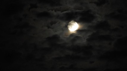 full moon at night with cloud real time. 4k video full moon in the black sky. clouds passing by moon