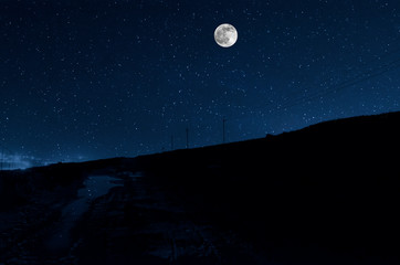 Wall Mural - Long exposure shot. Mountain Road through the forest on a full moon night. Scenic night landscape of dark blue sky with moon. Azerbaijan