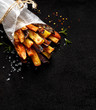 French fries,  baked fries from different types and colors of potatoes sprinkled with herbs and spices on a black background, top view, copy space