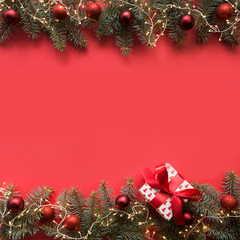 christmas frame with evergreen branches, red balls, gift on red