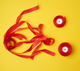 spools with red satin ribbon on a yellow background