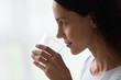 © fizkes - Closeup face of beautiful 30s woman holds glass of water