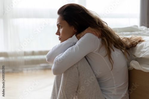 Fotografía Sad woman sitting on floor leaned on bed feels lonely