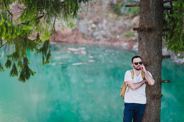 Bearded man model poses alongside a Green water Lake.