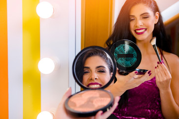 Pretty dark hair Caucasian woman applying making makeup with a gorgeous smile on her face