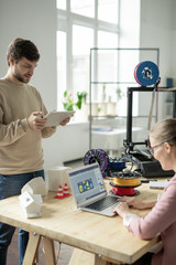 Canvas Print - Young designer with tablet scrolling through online stuff by workplace