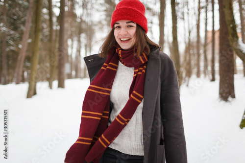 Fotografía Young woman with brown hair and gryffindor scarf is dancing in winter forest