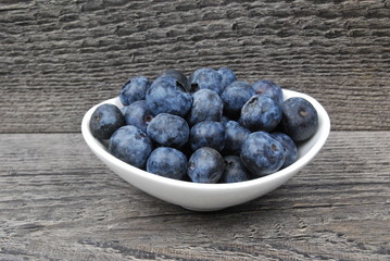 Dish of fresh blueberries on a rustic wood background