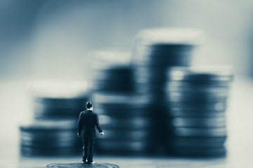 Poster - Close up miniature back businessman standing look up  money stack coin. Business finance growth concept.